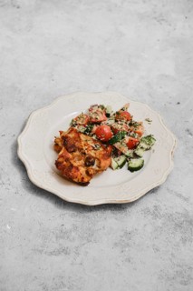 A delightful meal features a colorful salad with tomatoes and cucumbers placed beside a savory