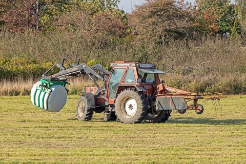 Tractor transporting bales of silage wrapped in film, Falshöft, Pommerby, Schleswig-Holstein,