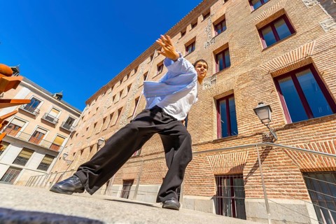 Young man actively performing a passionate flamenco move on a city street, expressing cultural