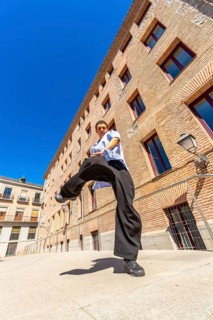 Young man doing a martial arts kick pose with focus and determination, dressed in casual loose