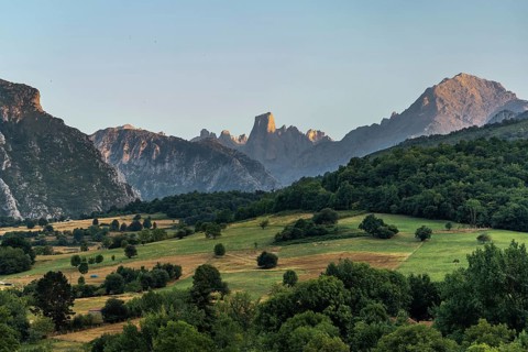 Golden hour sunlight illuminating the iconic naranjo de bulnes peak, towering over lush green
