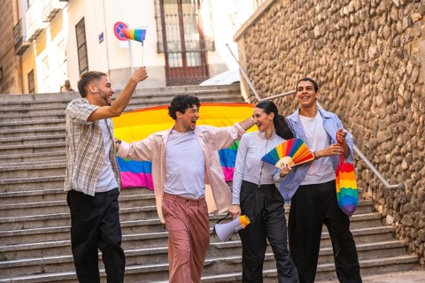 Diverse friendship group celebrating lgbtq plus pride and equality during a parade, walking down