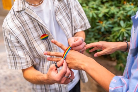 People are decorating their hands with rainbow colored adhesive tape, celebrating identity,