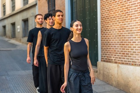 Young diverse dancers walking in line down a city street, smiling and energized while rehearsing