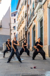 Group of four young dancers expressing movement and energy through a choreographed street