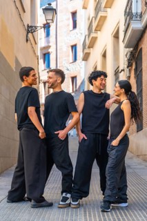 Four diverse young friends wearing black casual clothing are happily interacting, smiling, and