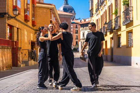 Group of young adult dancers rehearsing a modern dance performance on a cobbled street in a