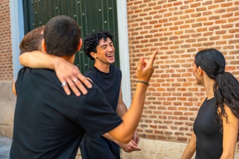 Group of diverse young adult friends embracing, laughing, and gesturing while enjoying a lively