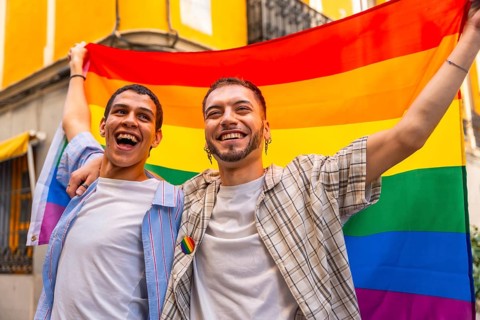 Happy young gay couple smiling, celebrating love, diversity, and lgbtq plus rights, holding a