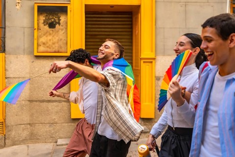 Group of diverse young people actively participating in a pride parade, expressing joy and holding