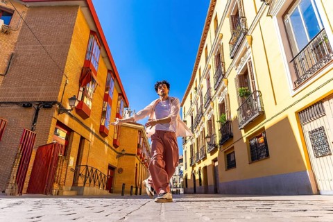 Young man freely dancing in a cobblestone street between traditional architecture buildings under a