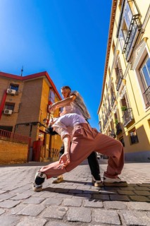 Two skilled dancers engaging in a passionate contemporary performance on a cobblestone street,