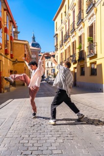 Two energetic young men performing a street dance on a cobblestone street in a lively european