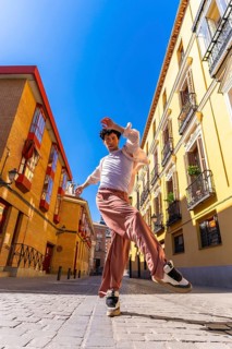 Young man dancer performing a dynamic street dance move in a vibrant old city urban setting under a