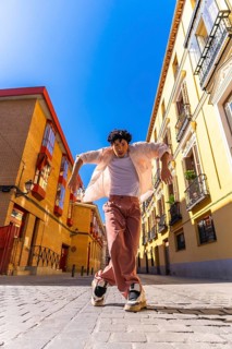 Stylish young man with intense expression executing a dynamic street dance move on cobblestones in
