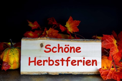 Wooden board with the inscription SCHÖNE HERBSTFERIEN and autumnal decoration