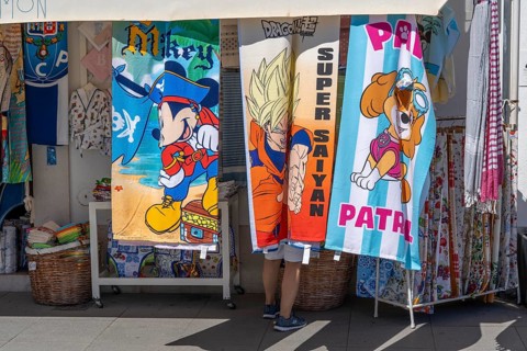 Tourists in a souvenir shop, bath towels with various comic motifs, in Vila Real de Santo António,