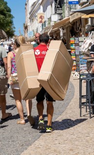 DPD courier, carrying parcels in the historic centre of Lagos, Algarve, Portugal, delivery on foot,