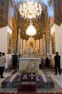 Worshippers gather in the richly decorated church with its large altar and chandeliers, Inside the