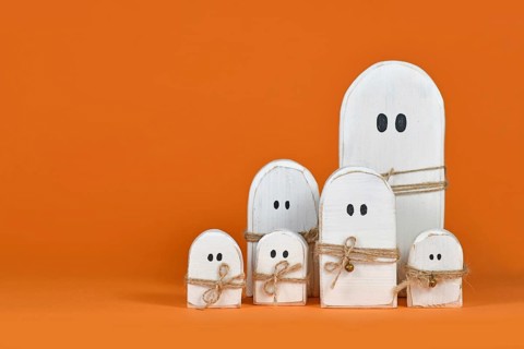Cute wooden white Halloween ghost ornaments on orange background