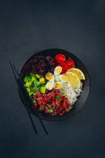 Fresh poke bowl with tuna, avocado, and vegetables served on a black plate