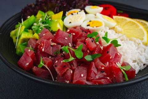 Fresh poke bowl with tuna, avocado, and vegetables served on a black plate