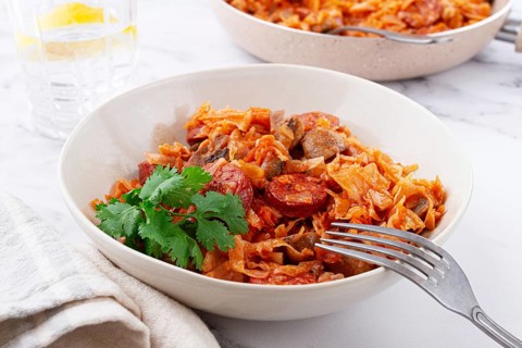 Bigos, Polish dish bigos, on the table, pan with stewed meat, with cabbage, chorizo sausages,
