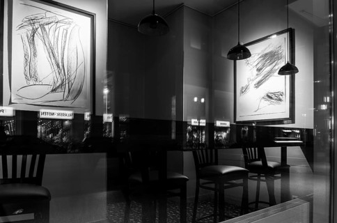 Black and white photograph, urban scene in the evening with reflections of Friedrichstraße in the