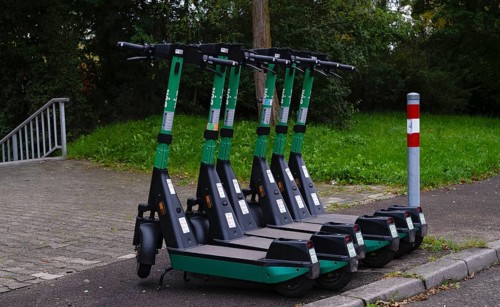 Several e-scooters, electric scooters, scooters parked on the pavement, pavement, in the Bolt bike