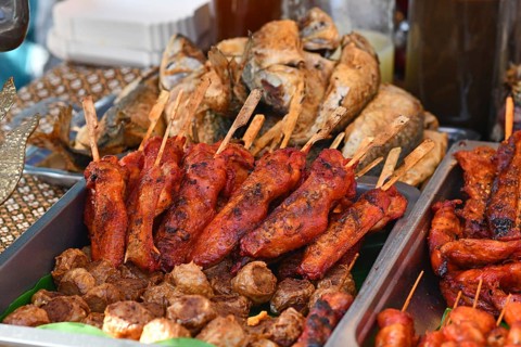 Grilled red marinated Thai chicken meat skewers at street food market