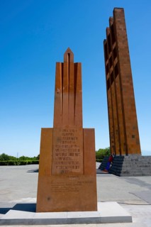 A tall red stone monument against a clear blue sky, Sardarapat Monument, Araks village, Armavir