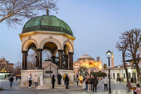 Tourists at the German Fountain or Kaiser Wilhelm Fountain and the Hagia Sophia at dusk, Istanbul,