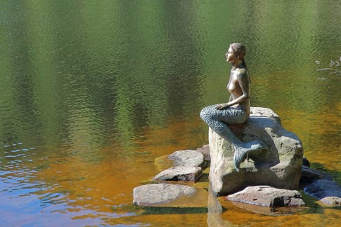 Mermaid sitting on a rock in the water, bronze sculpture, modern art, lake nymph, stone, Mummelsee,