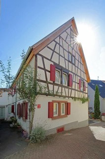 Half-timbered house with red shutters against the light, Höllgasse, Wiesloch, Baden-Württemberg,