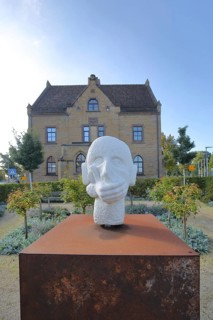 Sculpture head with headphones and hand for in front of the mouth, ambivalent symbolism for peace,