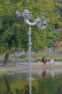 Sculpture Birdman by Albert Sous and two seated woman in conversation, people, pond, modern art,