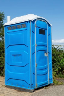 Blue and white portable chemical toilet temporarily installed by the roadside for public use in