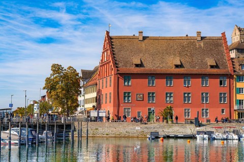 Historic building with red façade on the waterfront next to a harbour, Meersburg, Lake Constance,
