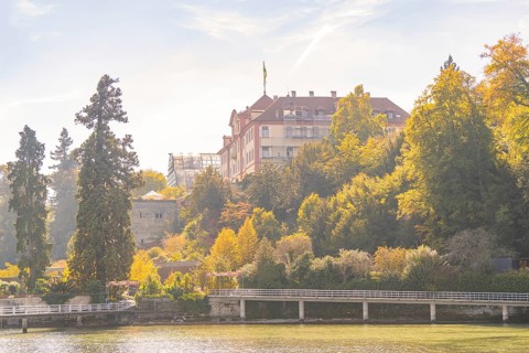 Castle on a wooded hill with autumnal trees, Mainau Island, Lake Constance, Germany
