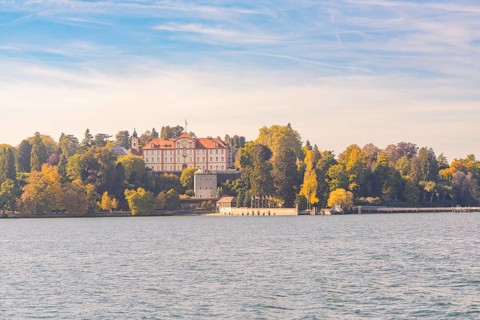 Sweeping view of the castle and autumnal forest by the lake, Mainau Island, Lake Constance, Germany