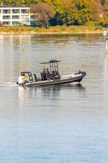 People in a police motorboat gliding across the calm lake on a sunny day, Constance, Lake
