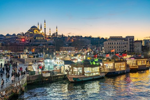 Restaurant boats on the shore of Eminönü, Rüstem Pasha Mosque and Suleymaniye Mosque at dusk,