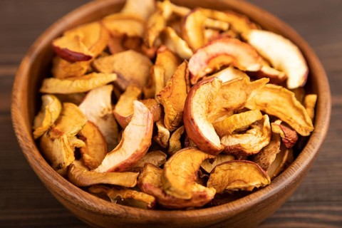 Dried Apples in wooden bowl on brown wooden background. Side view, close up, healthy food,