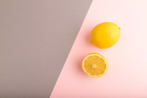 Yellow Lemon Cut in half on gray and pink pastel paper background. Top view, flat lay, copy space.