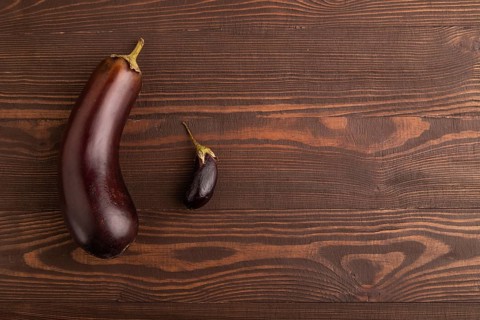 Two Eggplants big and small on brown wooden background, top view, flat lay, copy space, minimalism