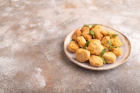 Fried crispy Chicken Nuggets with ketchup, microgreen on brown concrete background. side view, copy