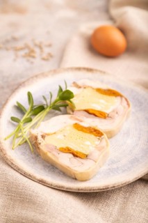 Chicken, egg and dried apricot meatloaf, microgreen on brown concrete background and linen textile.