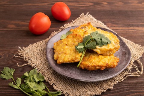 Fried crispy Chicken pancakes on brown wooden background and linen textile. side view, close up
