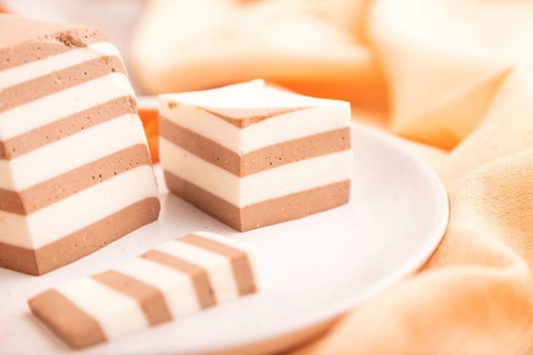 Cocoa and milk jelly with dried apricots on brown concrete background and orange textile, side