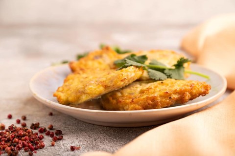 Fried crispy Chicken pancakes on brown concrete background and orange linen textile. side view,